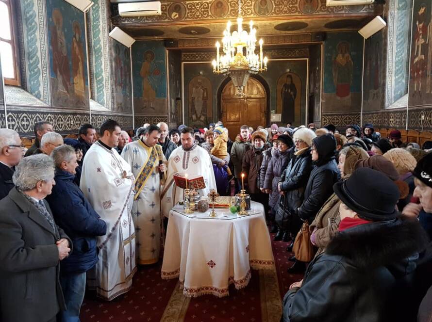 Sfințirea apei de Bobotează în biserica plină de credincioși, în jurul mesei pregătite pentru slujbă