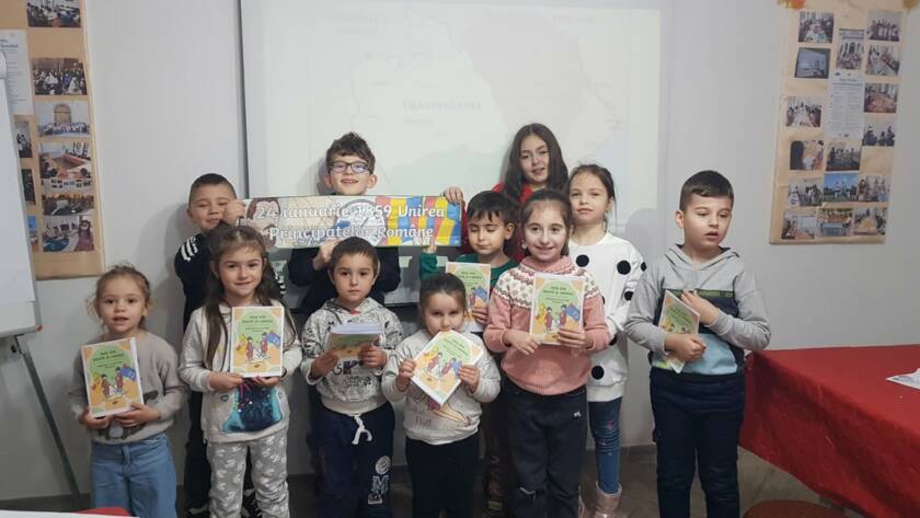 Grup de copii ținând calendarele realizate la atelier, în sala parohială