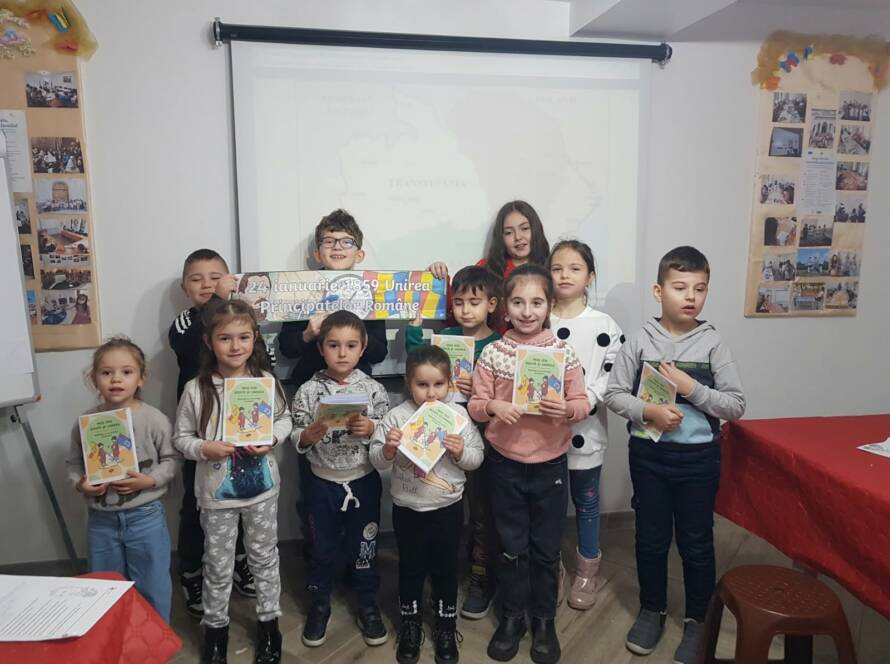 Grup de copii ținând calendarele realizate la atelier, în sala parohială