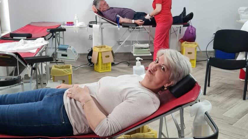 O donatoare pe patul de donare, în prim-plan, cu alți donatori și personal medical în fundal