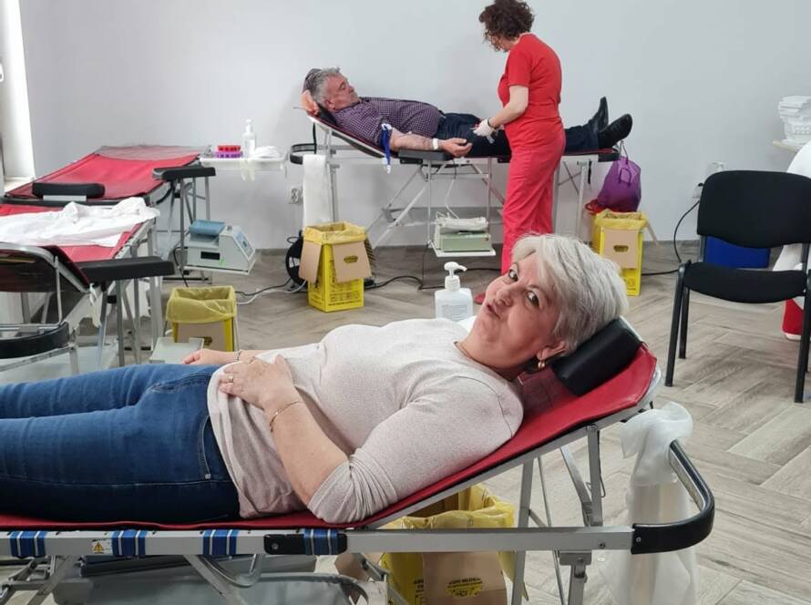 O donatoare pe patul de donare, în prim-plan, cu alți donatori și personal medical în fundal