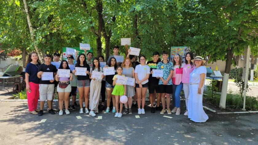 Fotografie de grup cu copiii și adulții, ținând diplome, în curtea bisericii