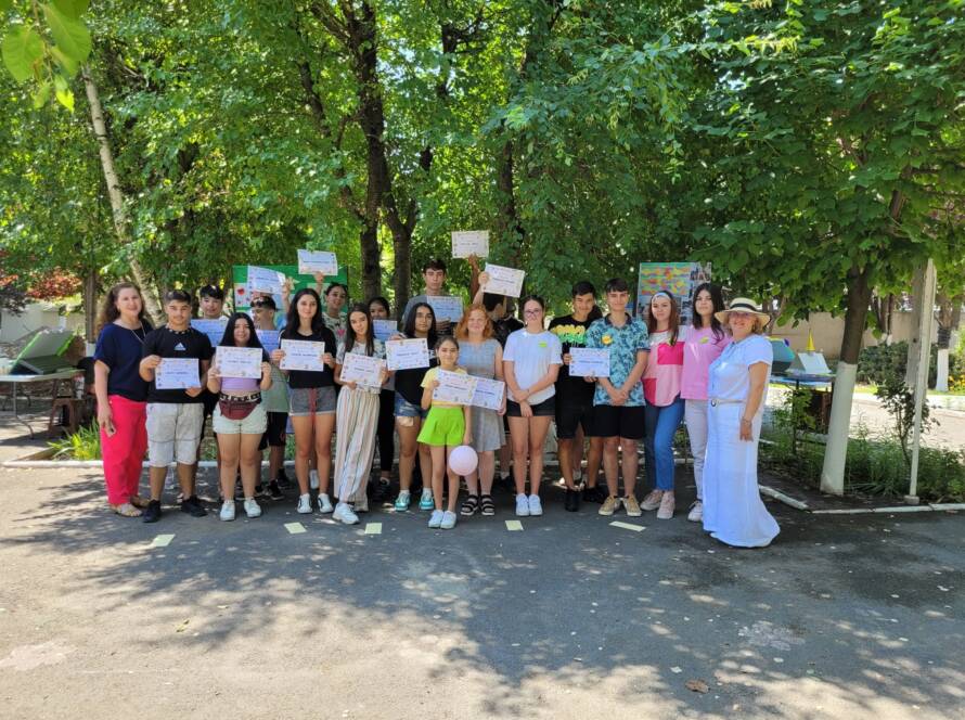 Fotografie de grup cu copiii și adulții, ținând diplome, în curtea bisericii