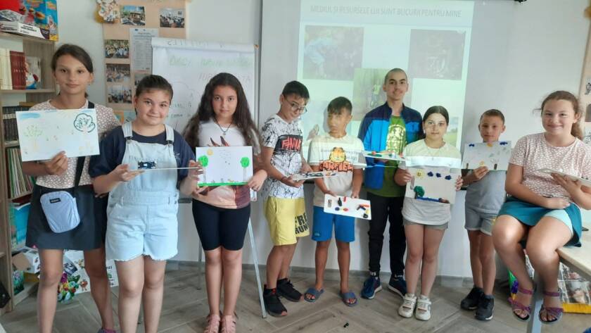Grup de copii arătând lucrările realizate, în sala parohială