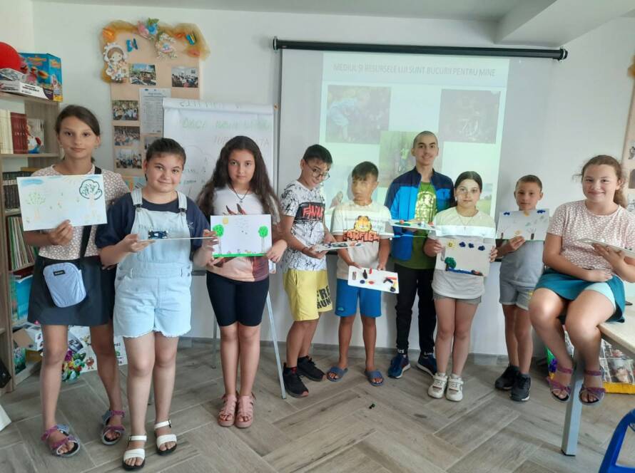 Grup de copii arătând lucrările realizate, în sala parohială