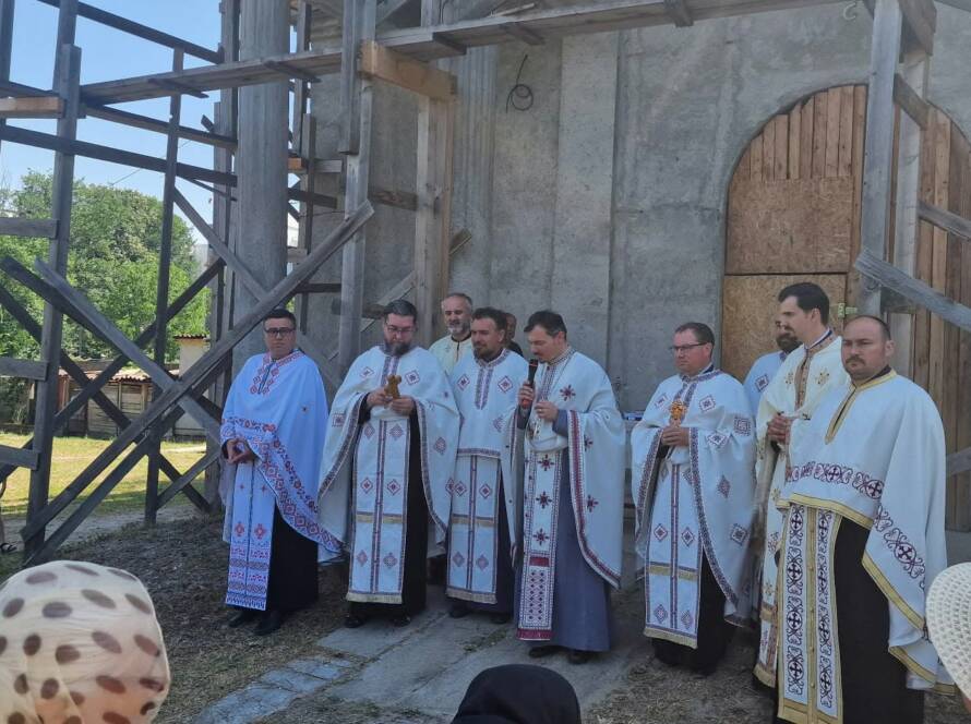 Preoții slujitori, în veșminte, în fața bisericii „Adormirea Maicii Domnului și Sfântul Mucenic Haralambie”