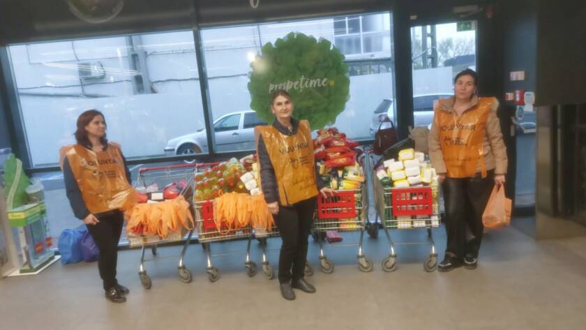 Voluntari alături de cărucioarele pline cu alimente strânse pentru persoanele vulnerabile