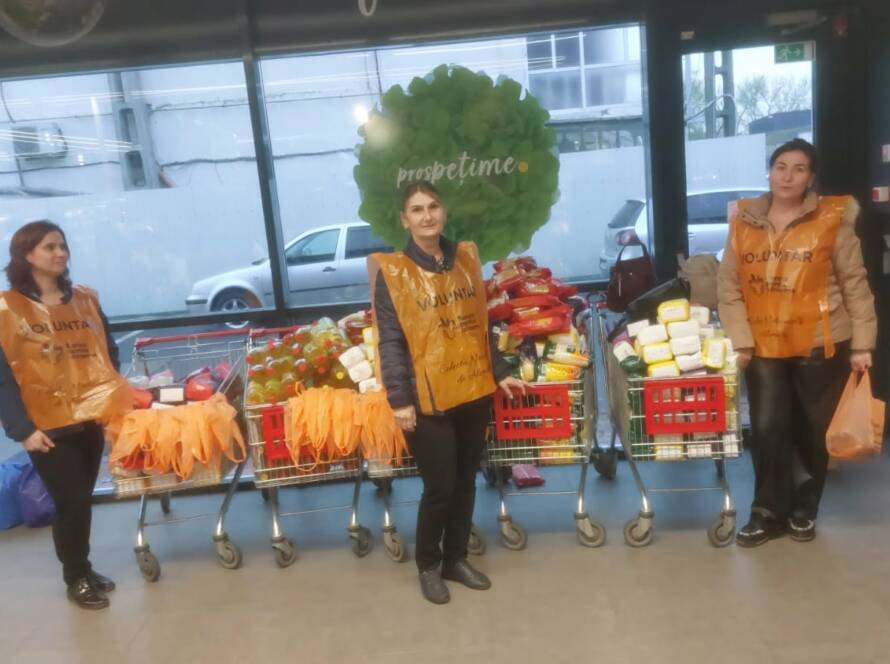 Voluntari alături de cărucioarele pline cu alimente strânse pentru persoanele vulnerabile