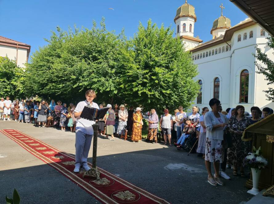 Un tânăr citește la strană în fața credincioșilor, în curtea bisericii, la sărbătoarea hramului.