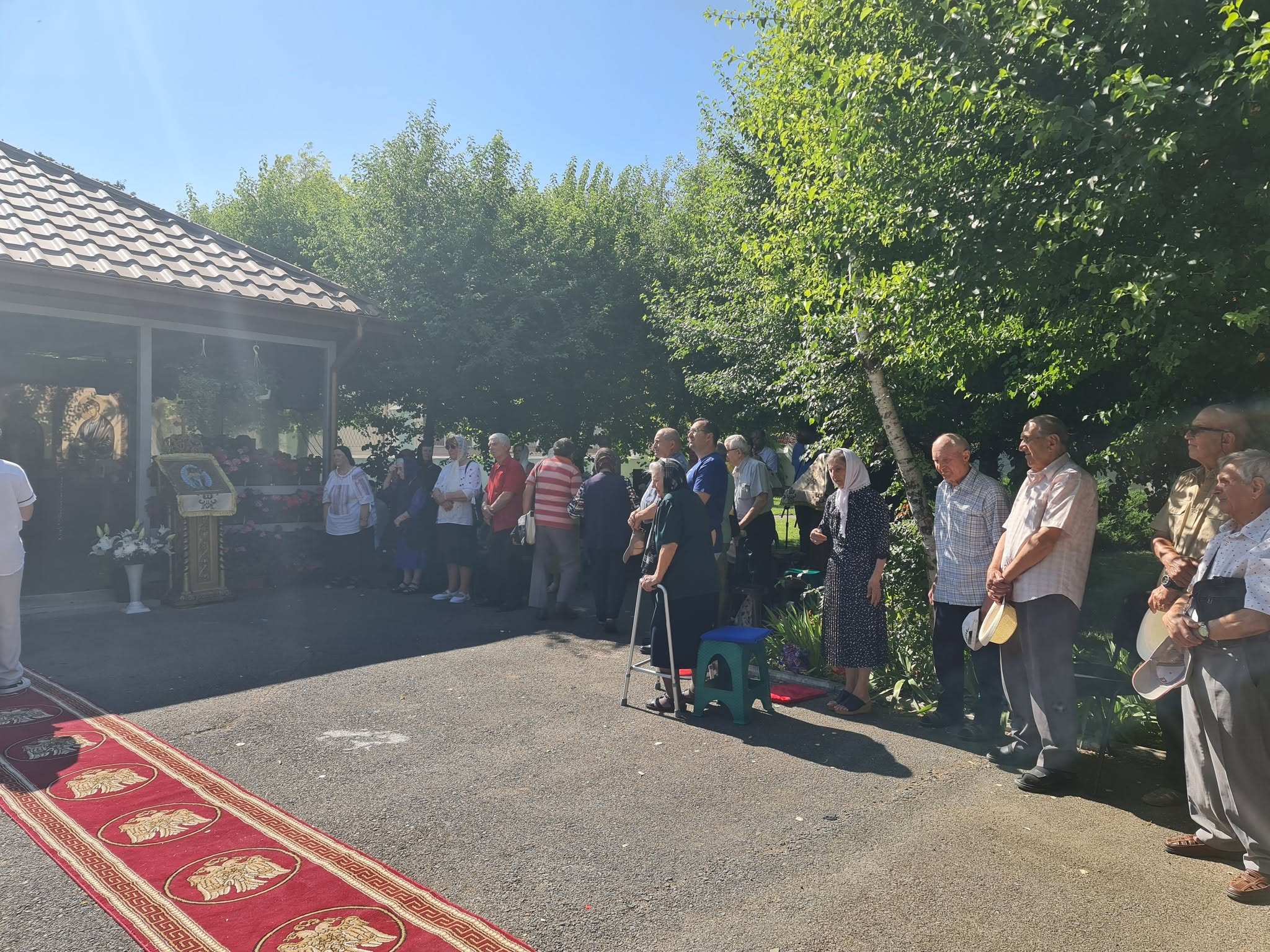 Credincioși participanți la slujba hramului, adunați în curtea bisericii.