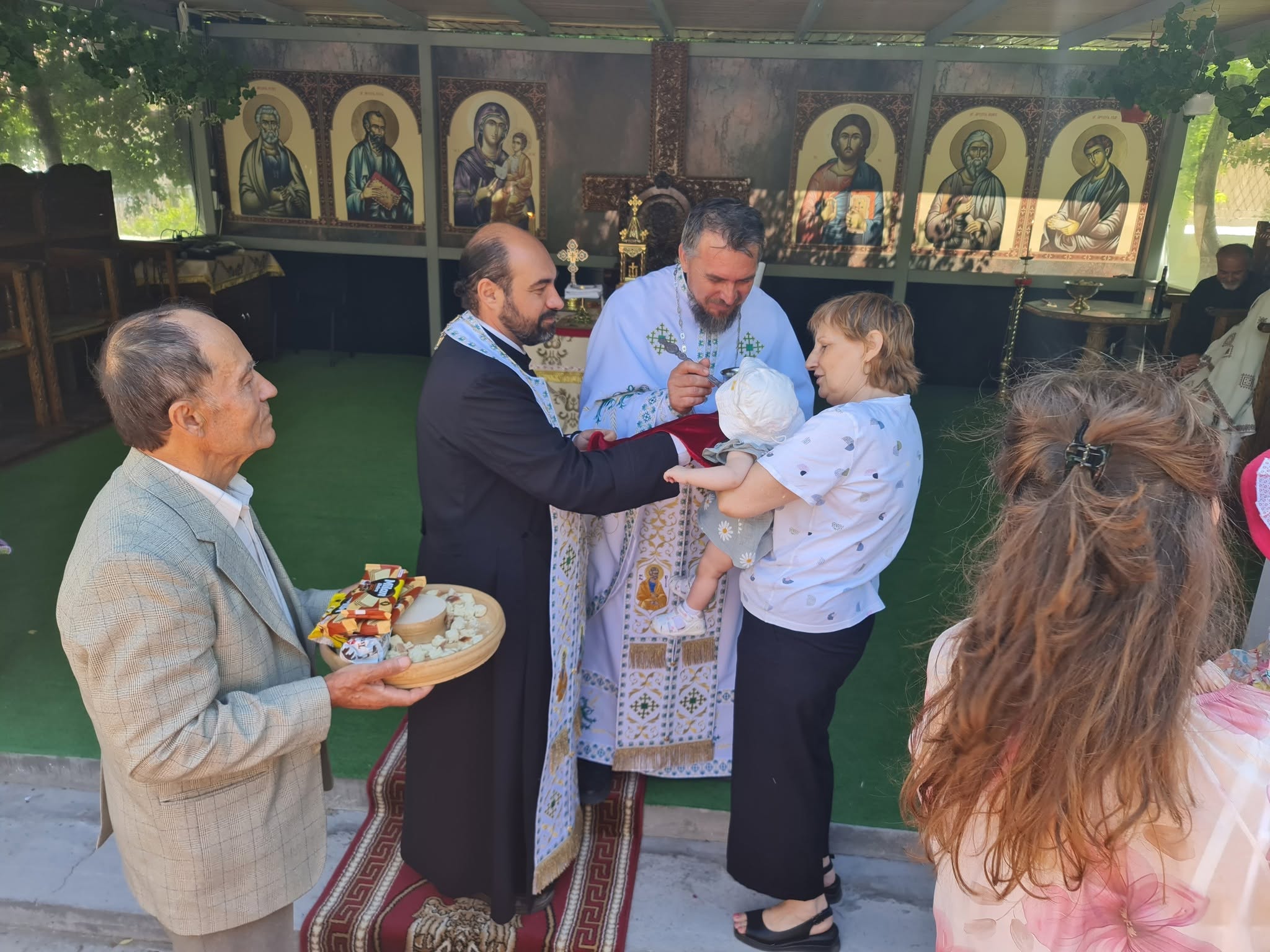 Un copil primește binecuvântare la altarul de vară după slujba hramului.