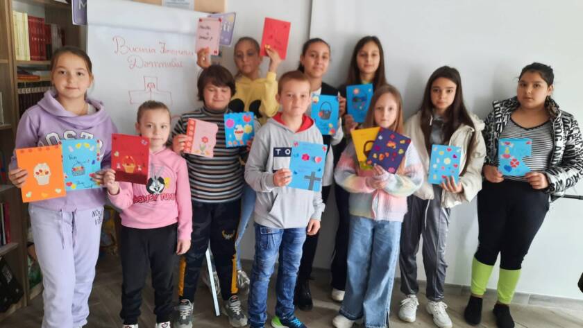 Grup de copii arătând felicitările de Paști realizate la atelier, în sala parohială