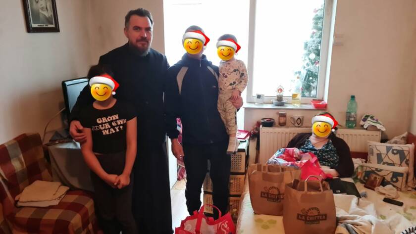Un preot alături de o familie și mai multe pachete cu alimente